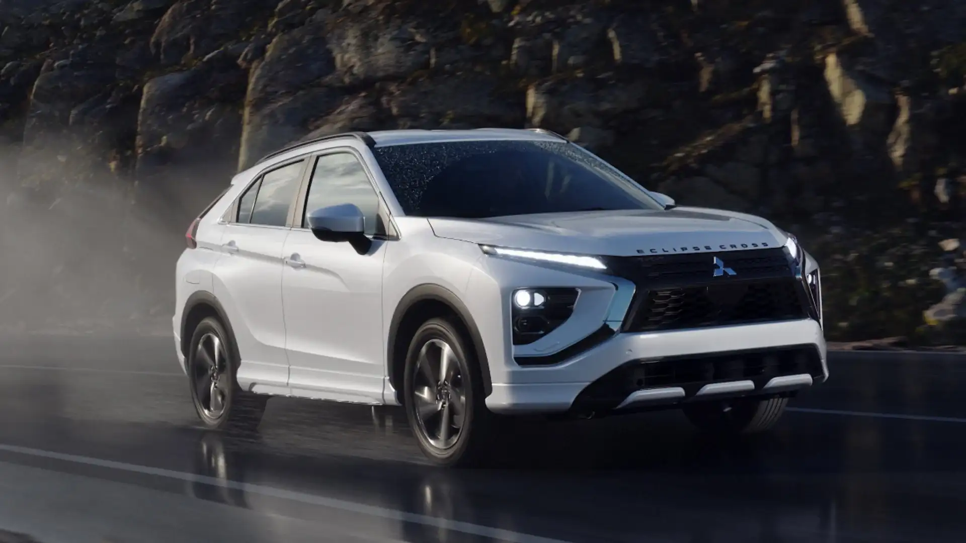 2026 Mitsubishi Eclipse Cross white SUV driving on wet road with LED lights and black grille