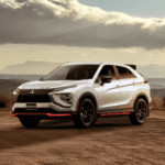 2026 Mitsubishi Eclipse Cross in white parked on scenic overlook with mountains and dramatic clouds.