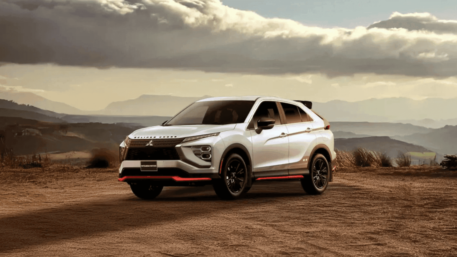 2026 Mitsubishi Eclipse Cross in white parked on scenic overlook with mountains and dramatic clouds.