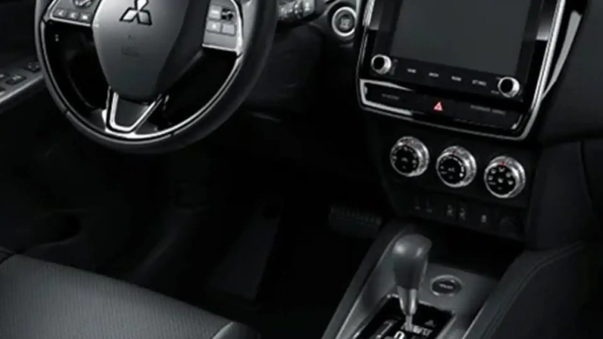 2026 Mitsubishi Outlander Sport cabin with steering wheel, touchscreen and climate controls visible.
