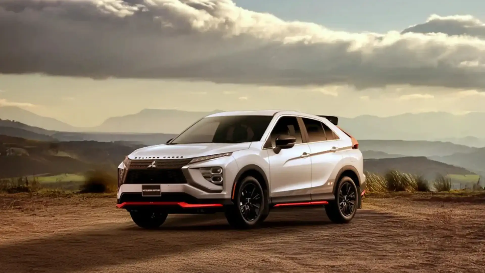 2026 Mitsubishi Eclipse Cross white SUV parked at a scenic mountain overlook beneath dramatic cloudy skies.