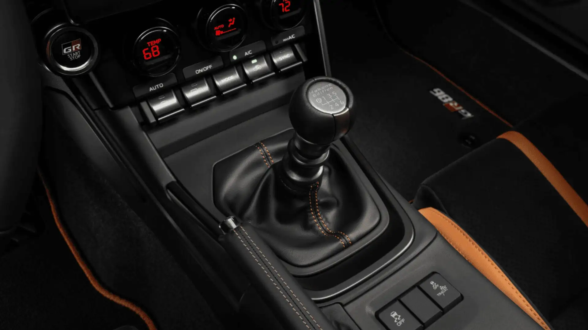 Close-up of the 2025 Toyota GR86 manual transmission shifter with sport stitching, performance controls, and GR branding inside the cabin.