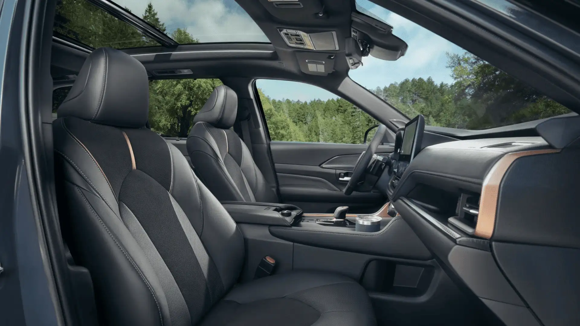 Front interior of the 2025 Toyota Grand Highlander featuring leather seating, a panoramic sunroof, and advanced infotainment technology.