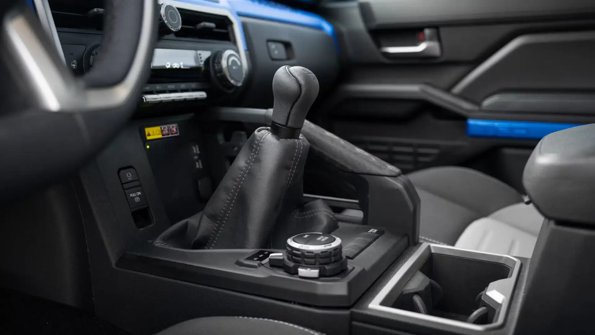 Close-up of the 2025 Toyota Tacoma interior featuring gear selector, drive mode knob, and modern driver technology controls.