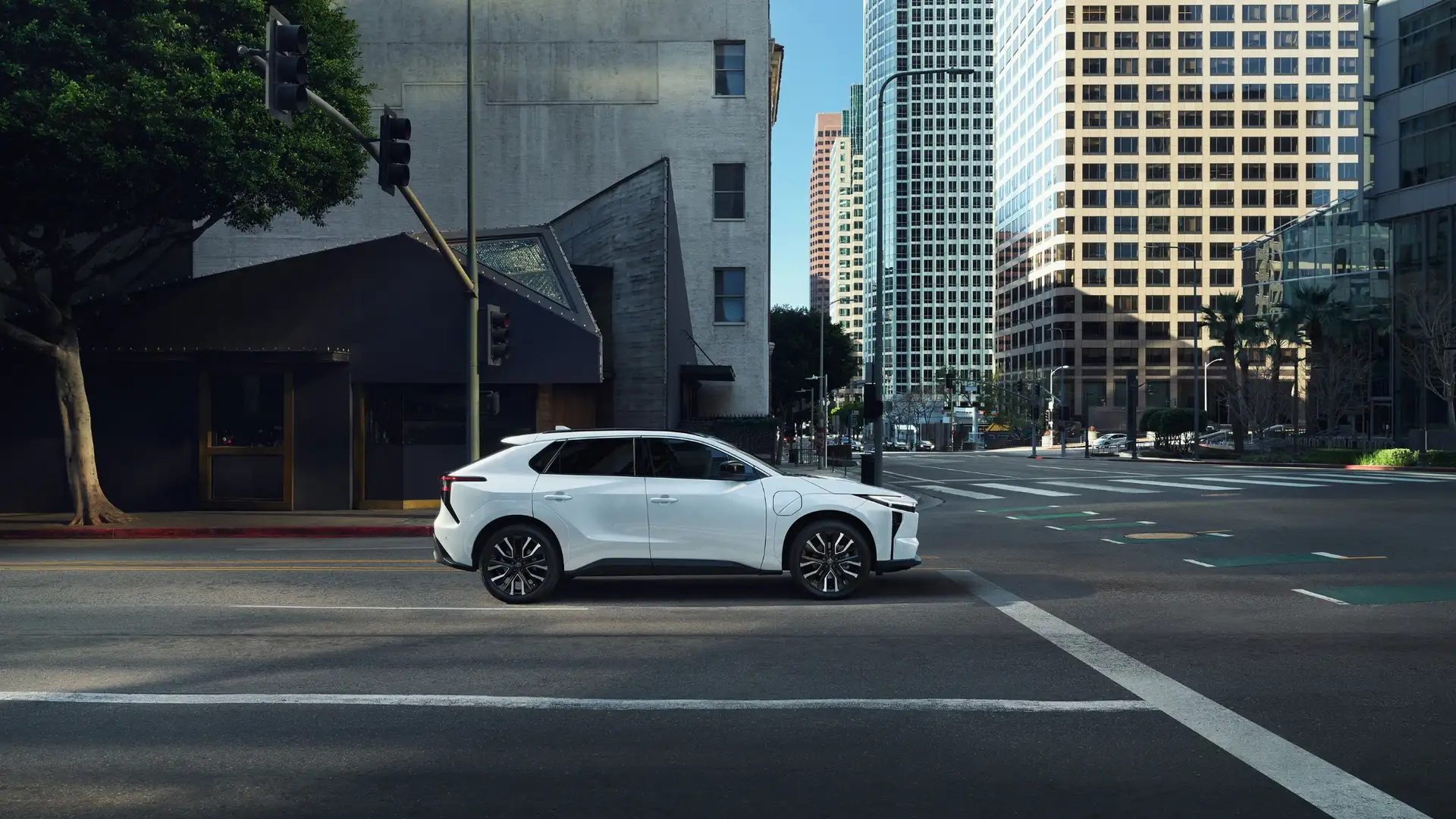 2026 Toyota bZ electric SUV driving in an urban setting near Greencastle, PA, displaying the sleek exterior profile and aerodynamic design