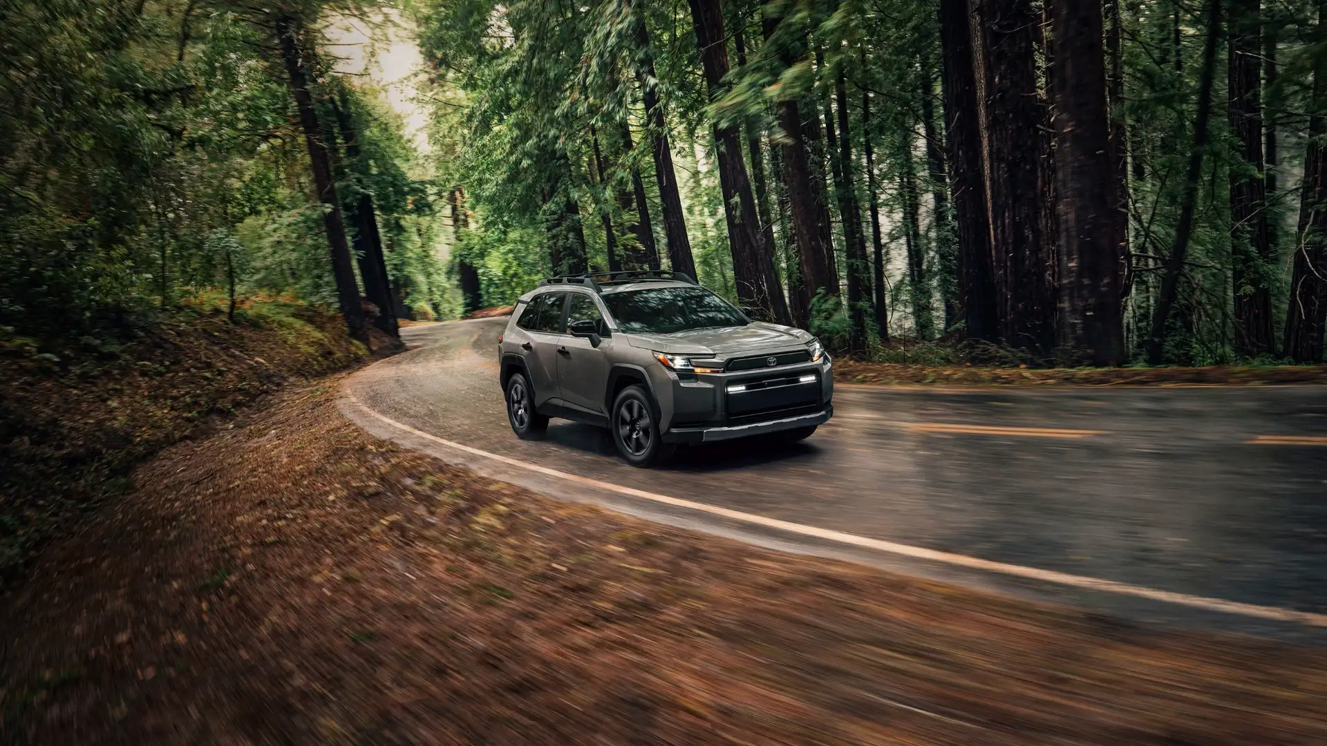 2026 Toyota RAV4 navigating a winding forest road, showcasing winter traction control and family-friendly performance near Greencastle, PA.