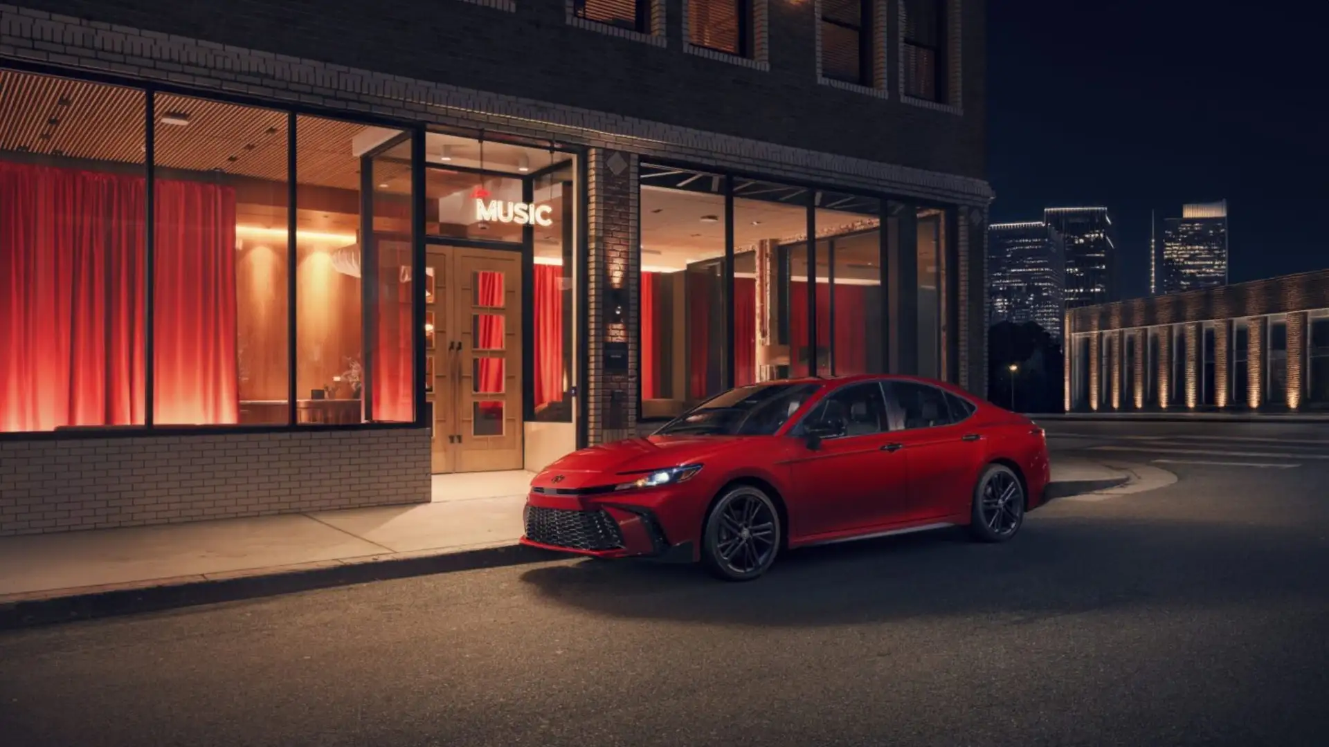 2025 Toyota Camry parked at night outside a modern building, highlighting stylish design and commuter appeal in Greencastle PA.
