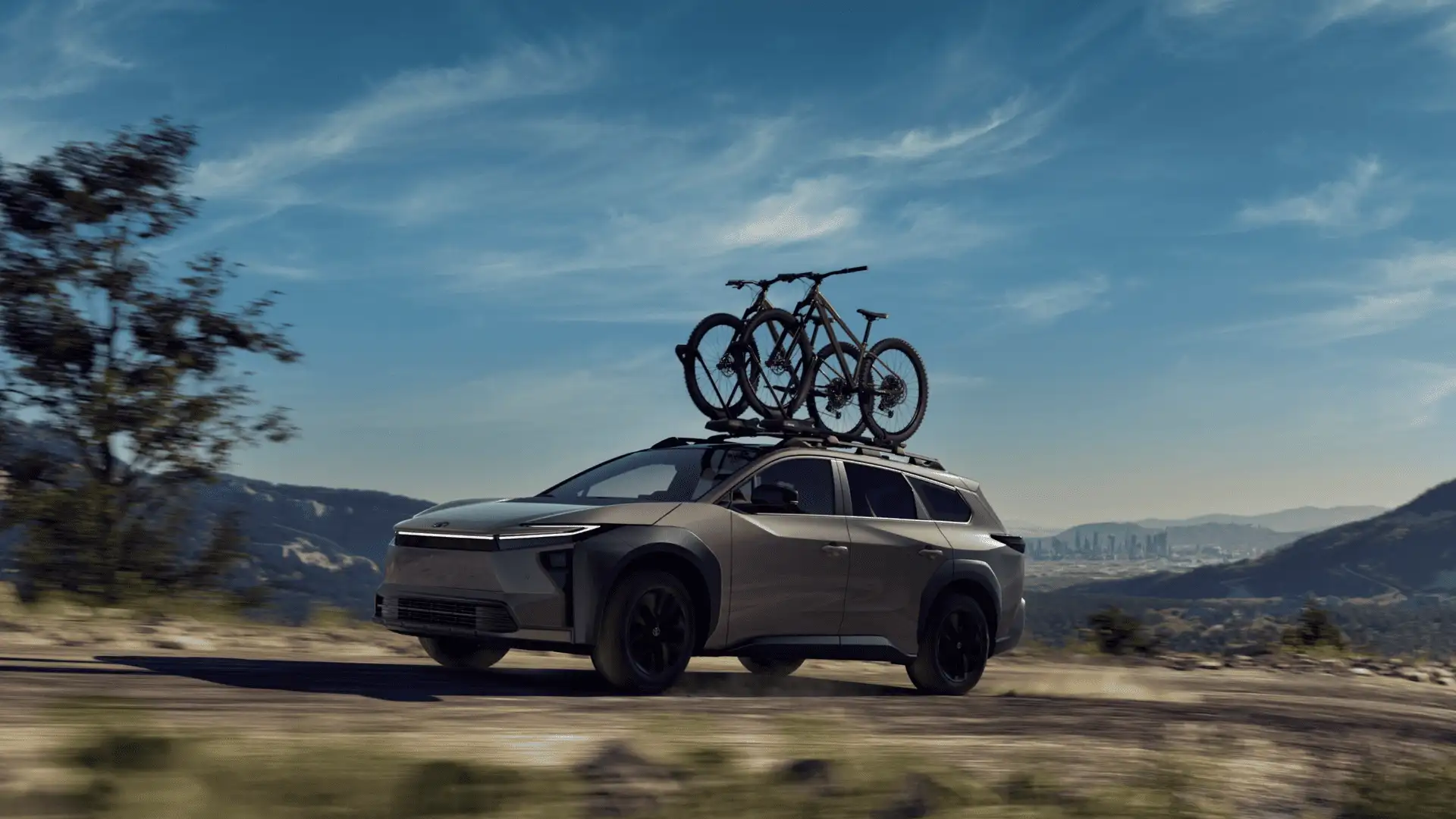 2026 Toyota bZ Woodland AWD driving with bicycles mounted on the roof, emphasizing all-wheel drive capability, outdoor versatility, and cold-weather range for Greencastle, PA winters.