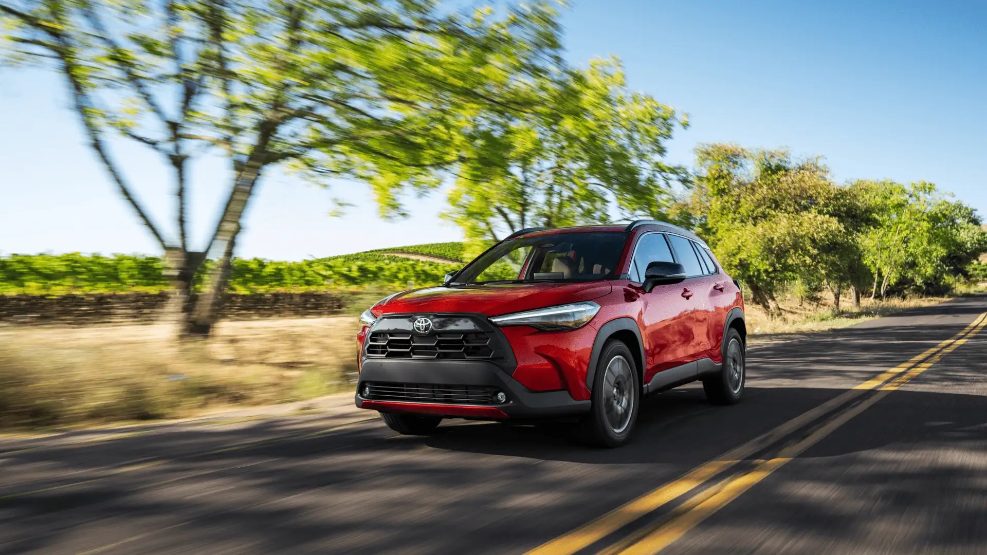 2026 Toyota Corolla Cross driving on a rural road, highlighting compact SUV performance, fuel efficiency, and everyday comfort for Greencastle, PA car shoppers.