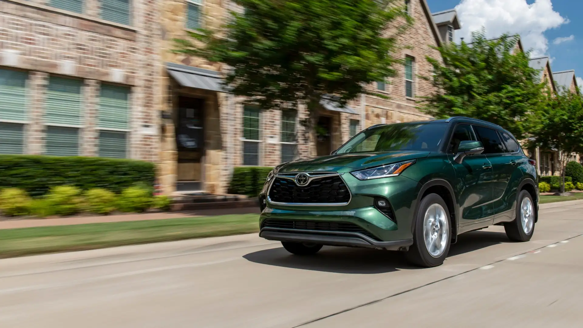 2025 Toyota Highlander Hybrid driving through a residential neighborhood, showcasing spacious interior and third-row seating for Hagerstown families