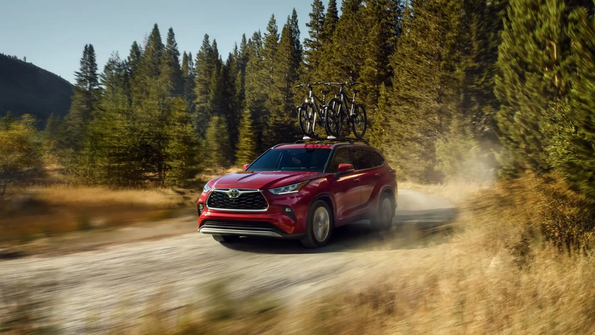 The 2025 Toyota Highlander in Hagerstown, MD driving on a dirt road with bicycles mounted on the roof, showcasing its family friendly SUV design and outdoor adventure capability.