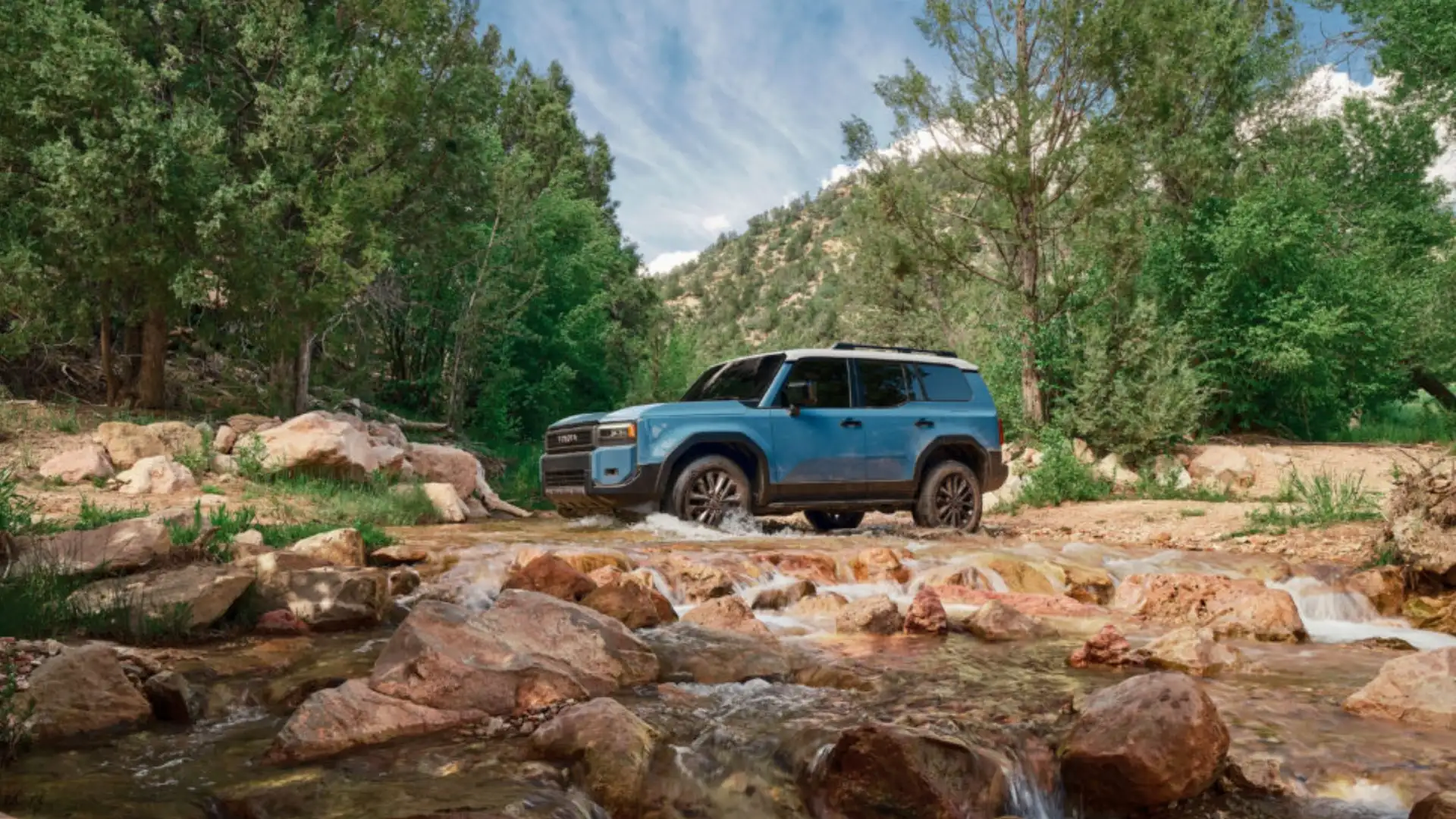 2025 Toyota Highlander Hybrid driving through a residential neighborhood, showcasing spacious interior and third-row seating for Hagerstown families