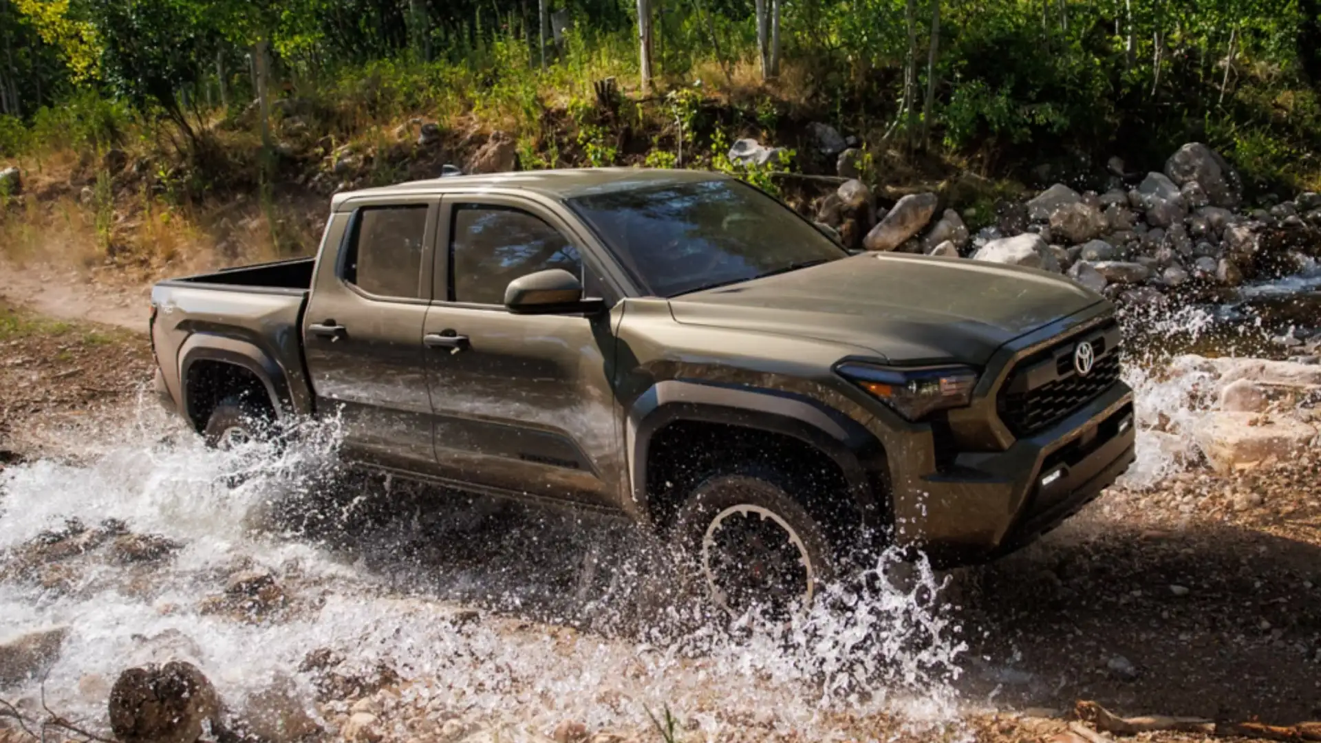 The 2025 Toyota Tacoma in Hagerstown, MD driving through a rocky creek, showcasing its off-road capability, rugged suspension, and trail-ready pickup design.