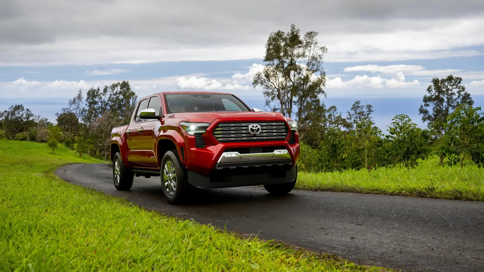 2026 Toyota Tacoma red pickup driving on scenic road highlighting capability and comfort compared to Nissan Frontier around Hagerstown MD