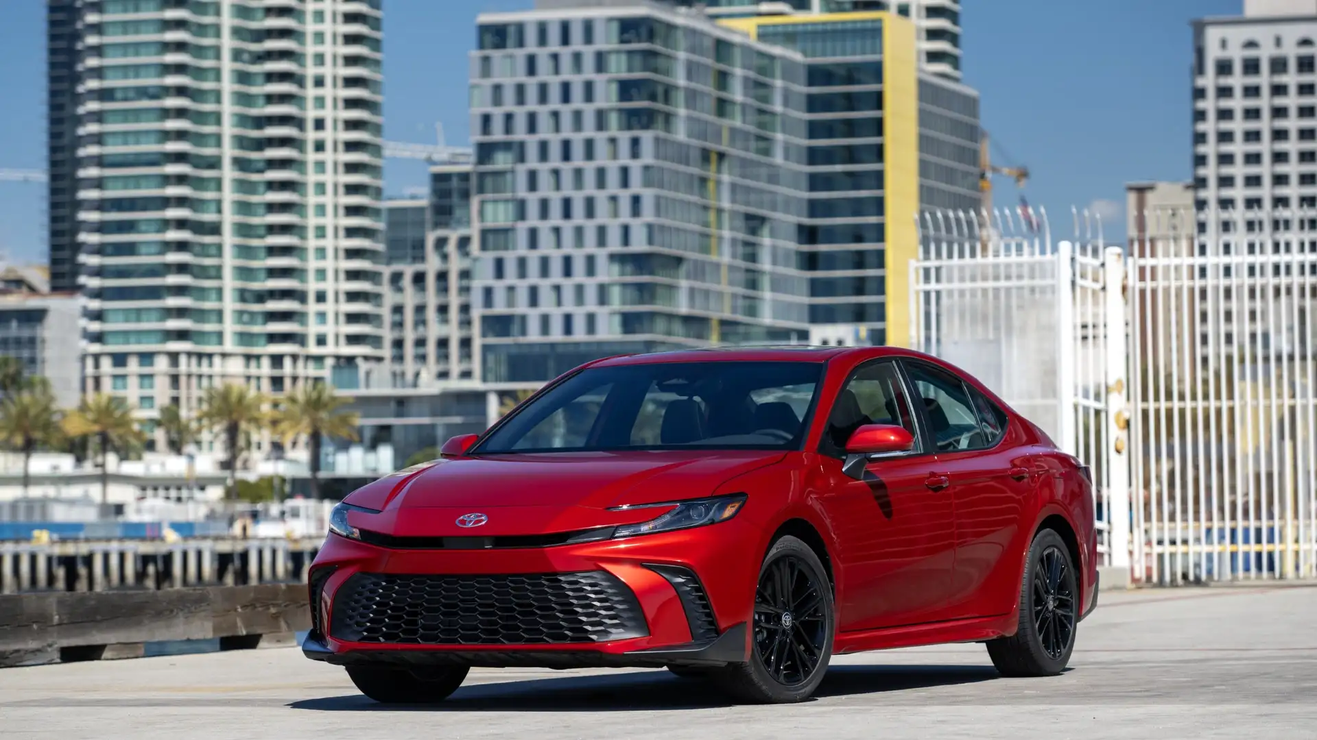 2026 Toyota Camry in red with black wheels parked near a waterfront cityscape in Hagerstown, MD.