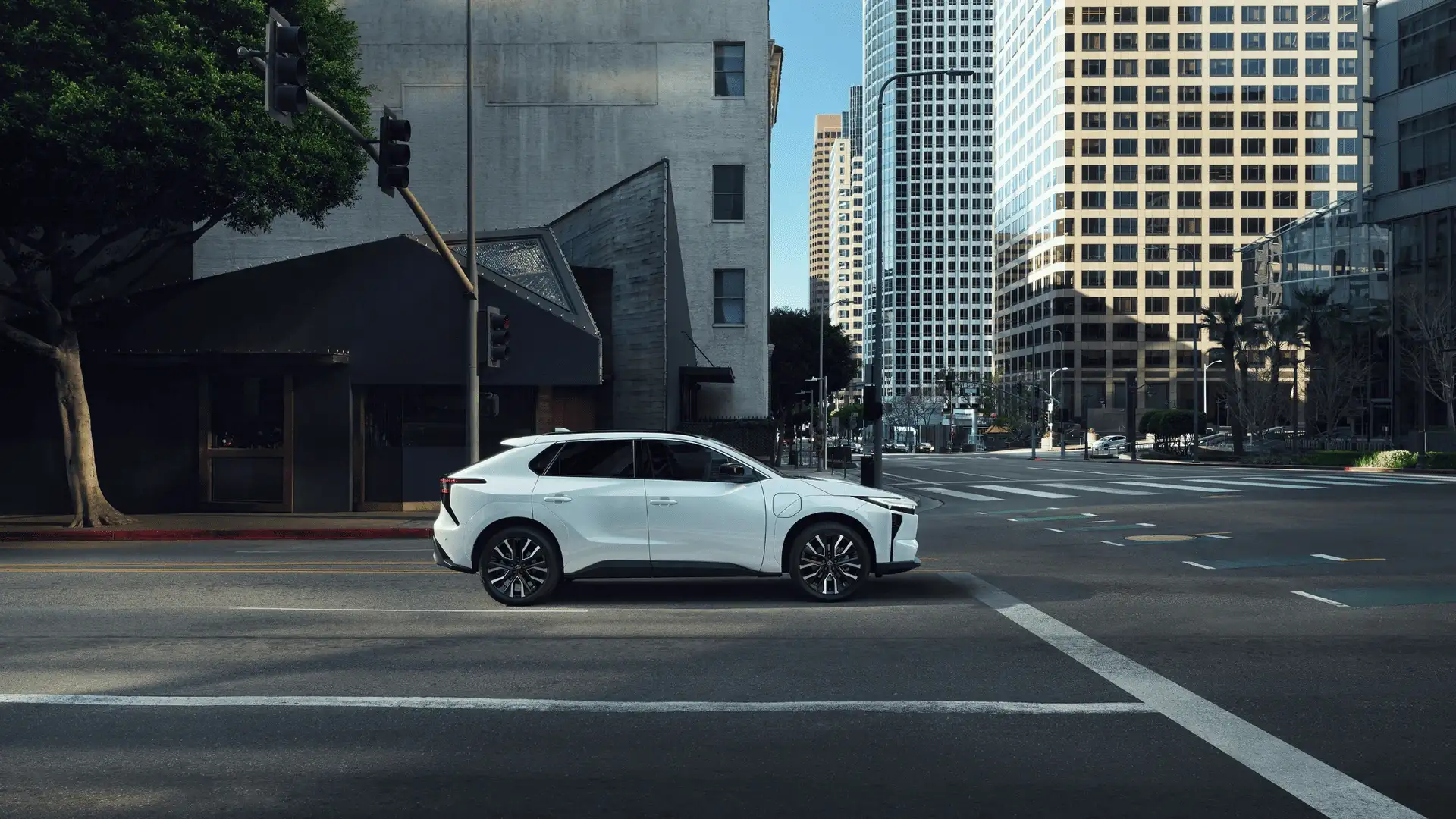 2026 Toyota bZ white electric SUV side profile driving city street in Hagerstown MD