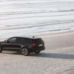 2025 Volvo V60 Cross Country wagon parked on beach shoreline with ocean waves in background