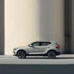 2025 Volvo XC40 compact SUV side view in light gray positioned between tall concrete walls