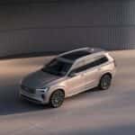 2025 Volvo XC90 luxury SUV angled exterior view in champagne color beside curved architectural wall